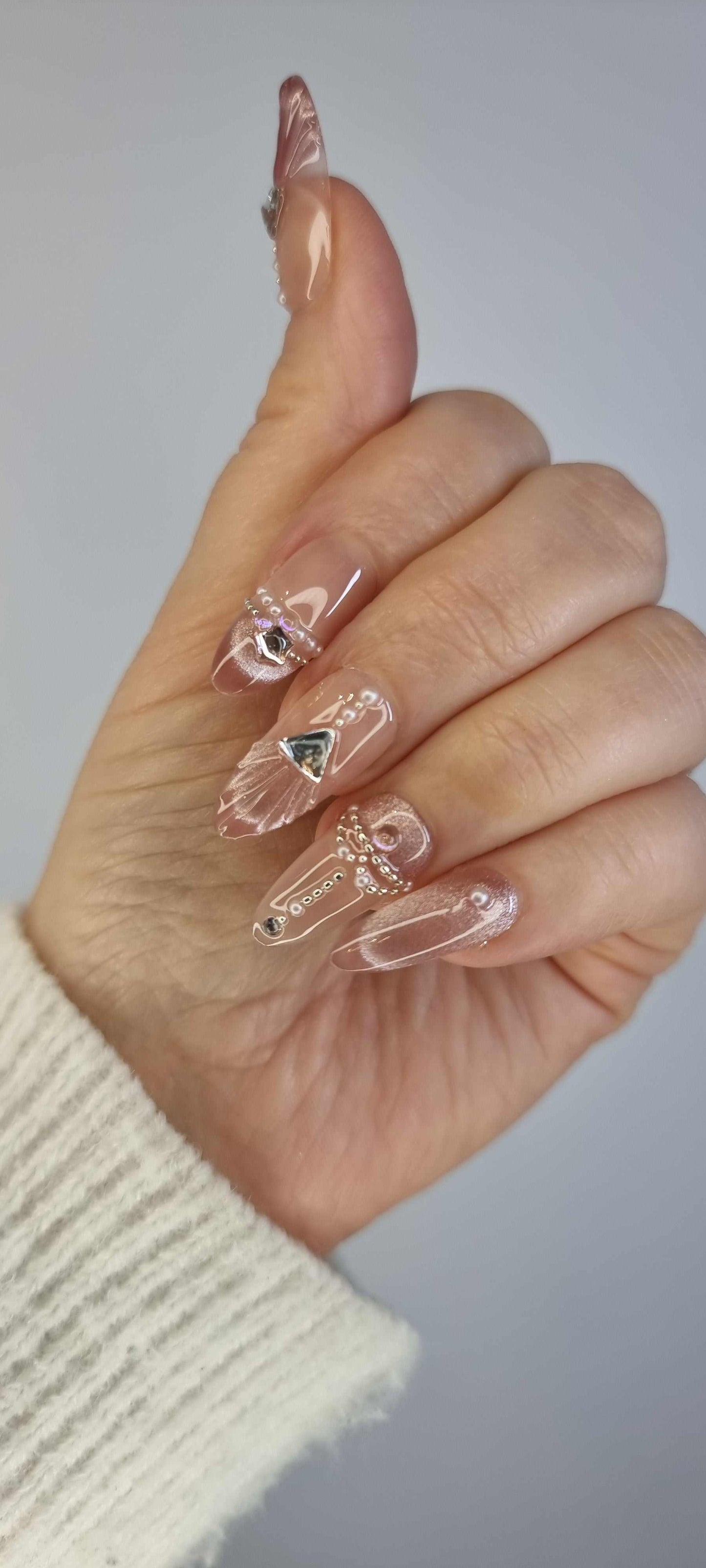 Close-up of Sharqiya Shine nude, almond-shaped press-on nails.