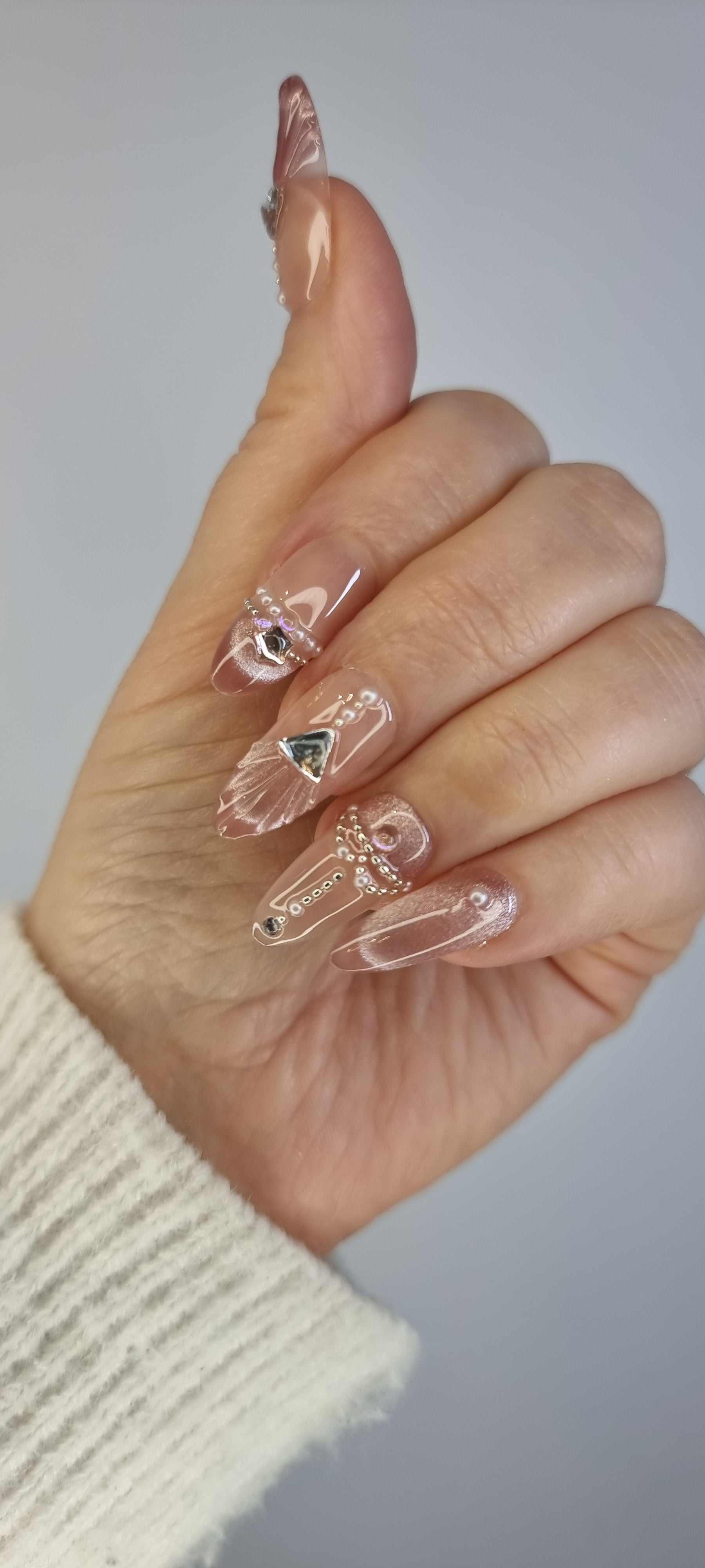 Close-up of Sharqiya Shine nude, almond-shaped press-on nails.