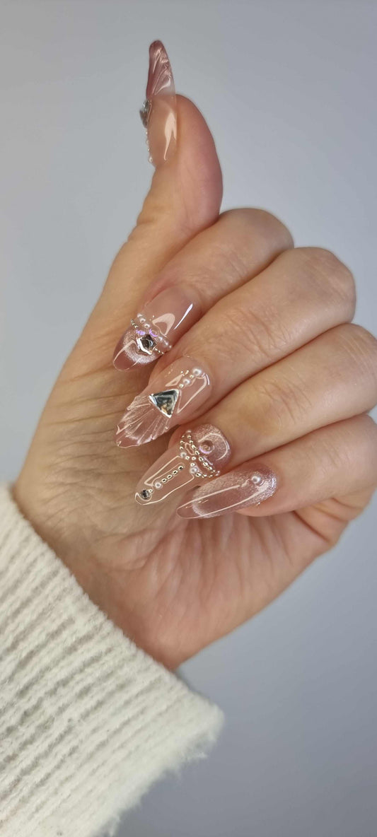 Close-up of Sharqiya Shine nude, almond-shaped press-on nails.