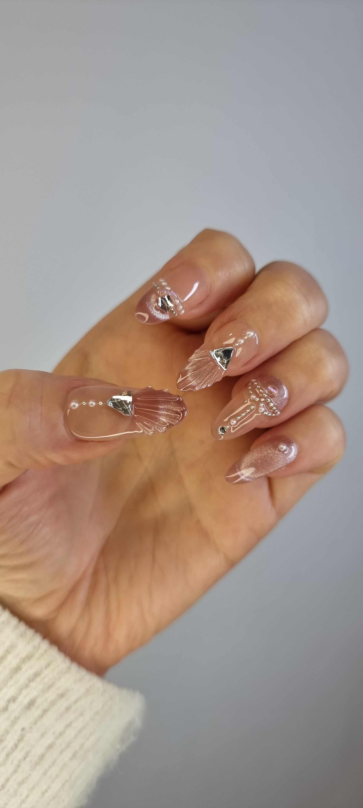 Set of Sharqiya Shine nude, almond-shaped press-on nails, showing the finished look.