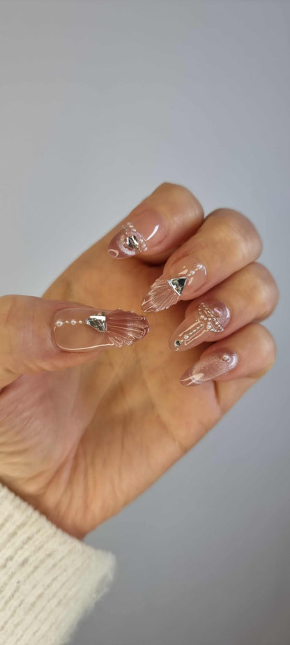 Set of Sharqiya Shine nude, almond-shaped press-on nails, showing the finished look.