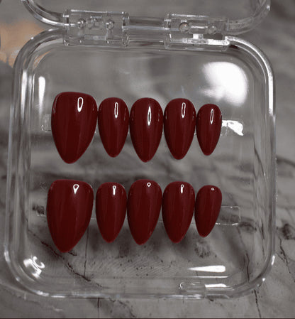 Set of red nail polish in a clear case on a marble surface