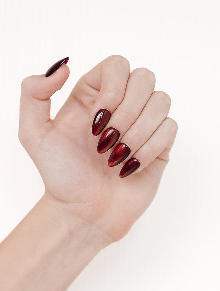 Hand with burgundy nail polish on a white background