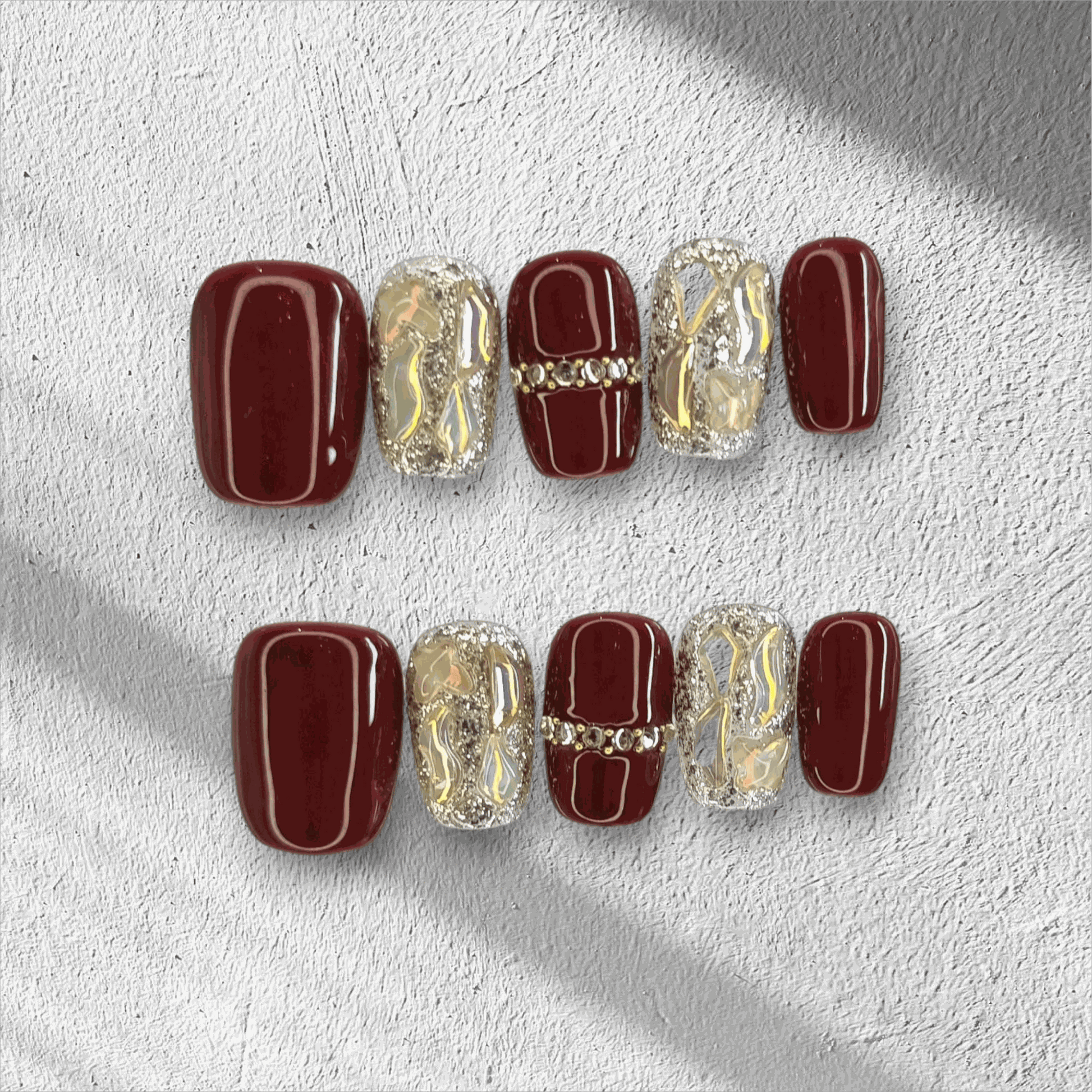 Full set of the Zaina red short square press-on nails, some with designs.