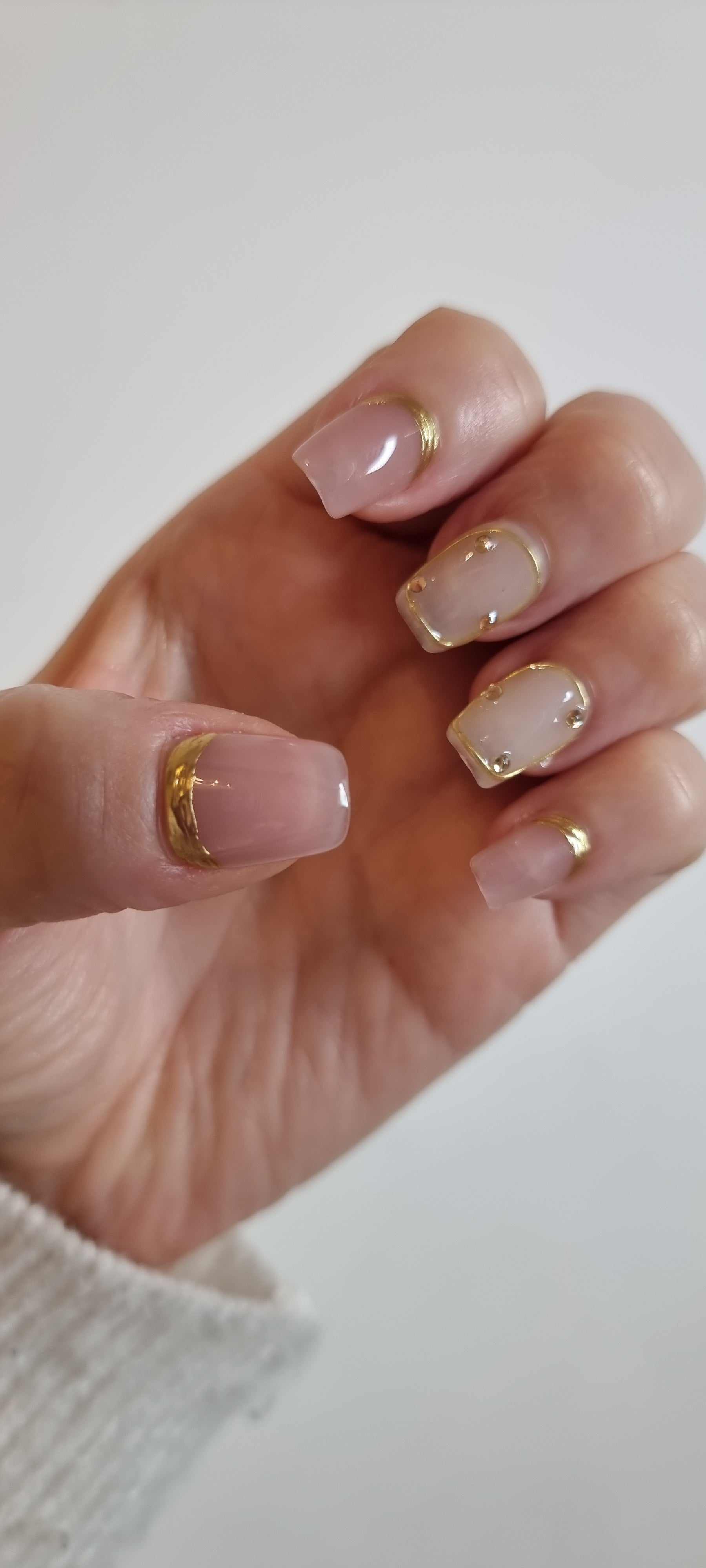Close-up of a model's hand wearing the Zina nude artificial nails with a glossy finish.