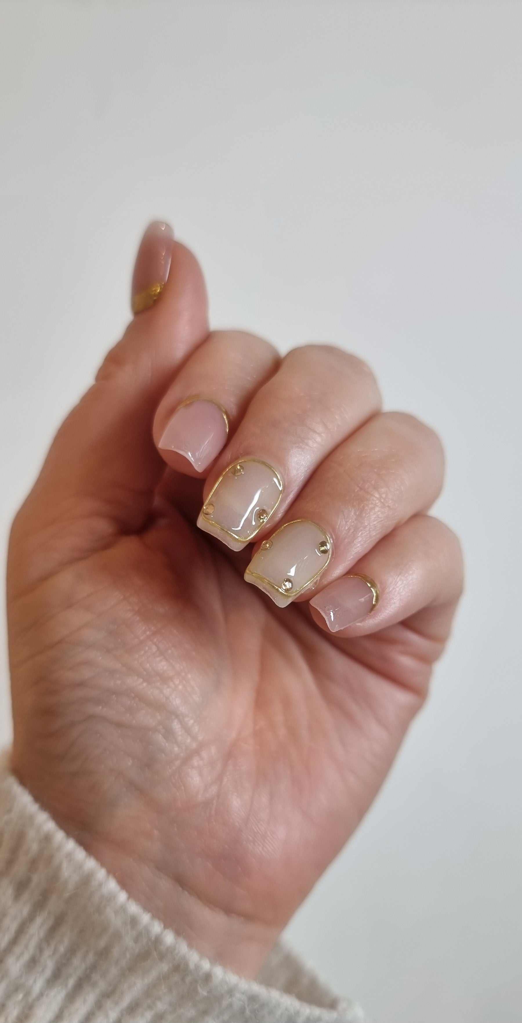 Close-up of a model's hand wearing the Zina nude artificial nails.