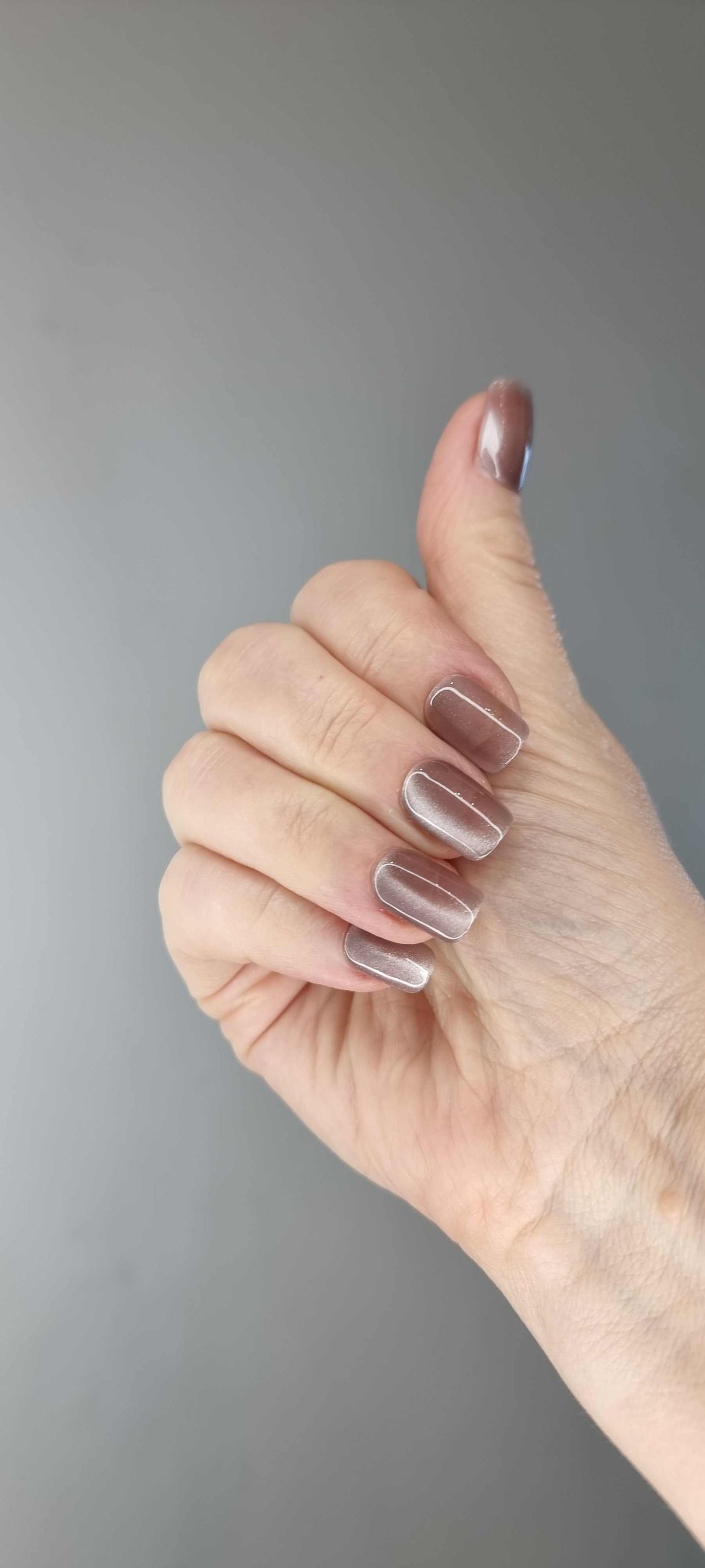 A set of Zubaida nude beige false press-on nails with a subtle, delicate design  on a model's hand.